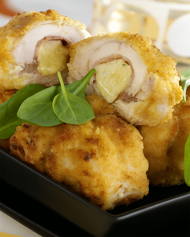 Escalopes de poulet aplaties, farcies d'une tranche de jambon et d'un bâtonnet de mozzarella, prêtes à être roulées.
