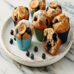 Muffins aux Bananes et Bleuets doré, cuit à la friteuse à air chaud, avec une croustille de banane sur le dessus.