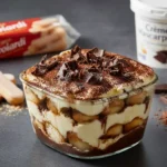 Ingrédients pour tiramisu poires chocolat : mascarpone, œufs, poires Williams, biscuits et chocolat noir sur une table de cuisine.